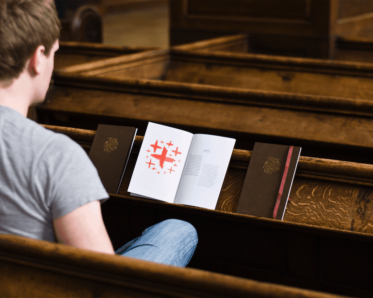Person sat on a pew with a book infront of them